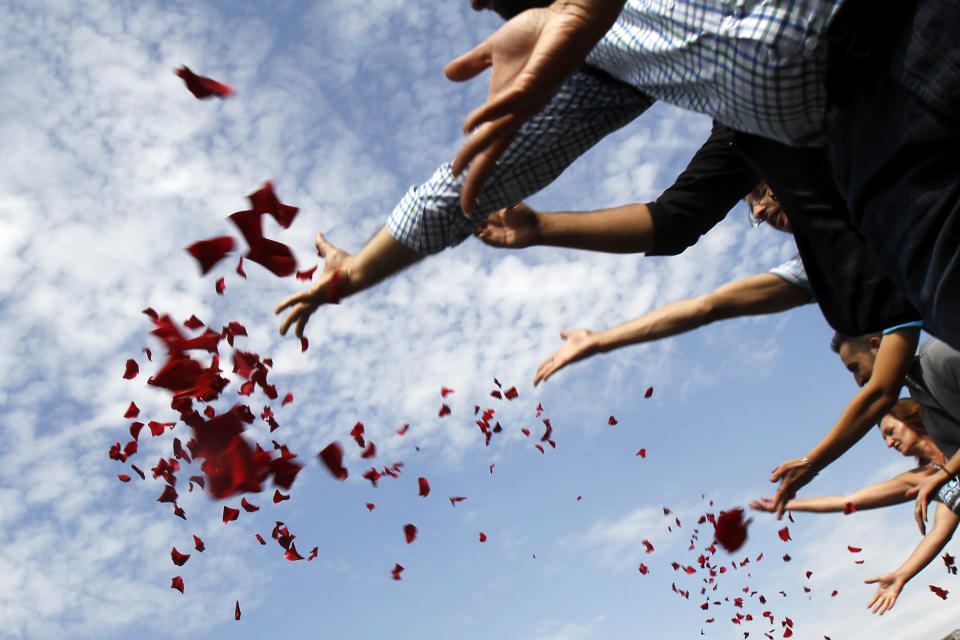 Members of Romania's ethnic Roma minority throw flower petals into Dambovita river during a commemoration ceremony next to the Holocaust Memorial in Bucharest August 2, 2012. Members of the Roma minority commemorated the 68 years since thousands of ethnic Roma people were killed at the Auschwitz-Birkenau concentration camp by Nazi Germany during World War II. REUTERS/Bogdan Cristel (ROMANIA - Tags: SOCIETY ANNIVERSARY)