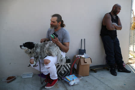 Daniel McMillan, 45, (L) who has been homeless for 20 years, sits with his dog on the street where he lives in Hollywood, Los Angeles, California, U.S. March 29, 2018. REUTERS/Lucy Nicholson