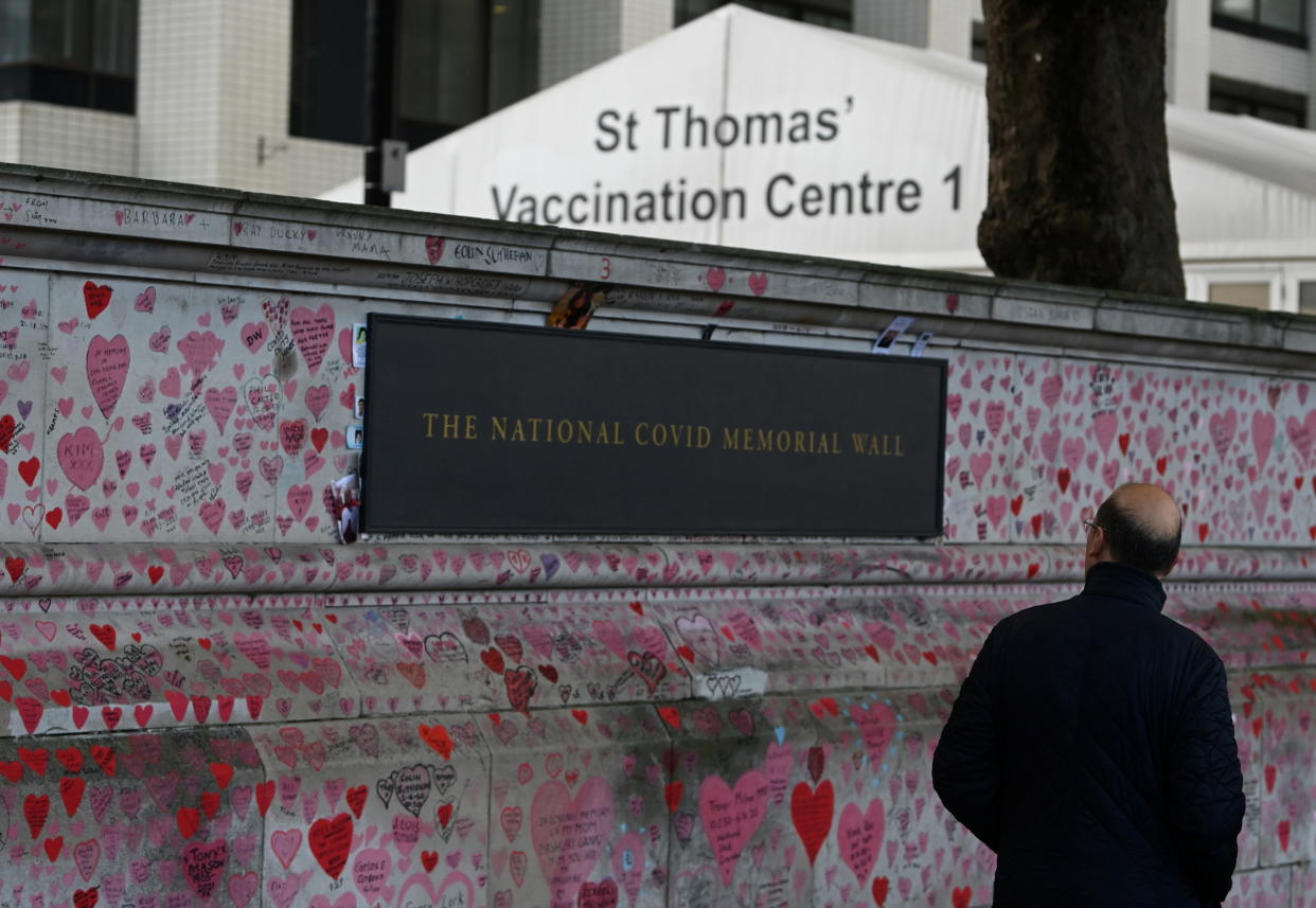 A man views the National Covid Memorial Wall, a dedication of thousands of hand painted hearts and messages commemorating victims of the COVID-19 pandemic, with a Covid vaccination centre at St Thomas' Hospital seen behind, in London, Britain, October 20, 2021. (Toby Melville/Reuters)