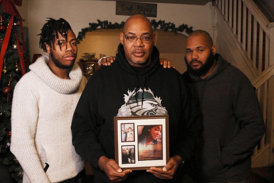 Leroy West, holding a photo of his daughter Robin West. He is in his Philadelphia home flanked by his sons and Robin's brothers, Azrien, 21, and Raymond, 27.