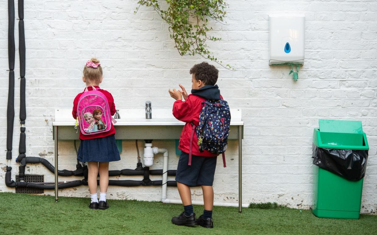Pupils wash their hands as they arrive on the first day back to school at Charles Dickens Primary School in London