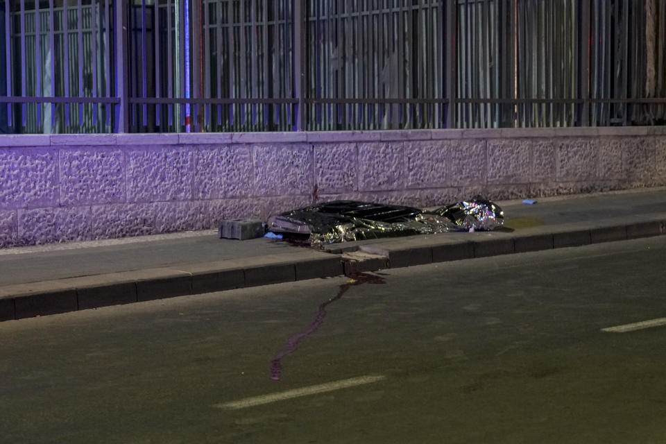 A body is covered on the side walks after a shooting attack near a synagogue in Jerusalem, Friday, Jan. 27, 2023. A Palestinian gunman opened fire outside an east Jerusalem synagogue Friday night, killing five people and wounding five others in one of the deadliest attacks on Israelis in years, medical officials said. The attack was halted when the gunman was shot by police. (AP Photo/Mahmoud Illean)