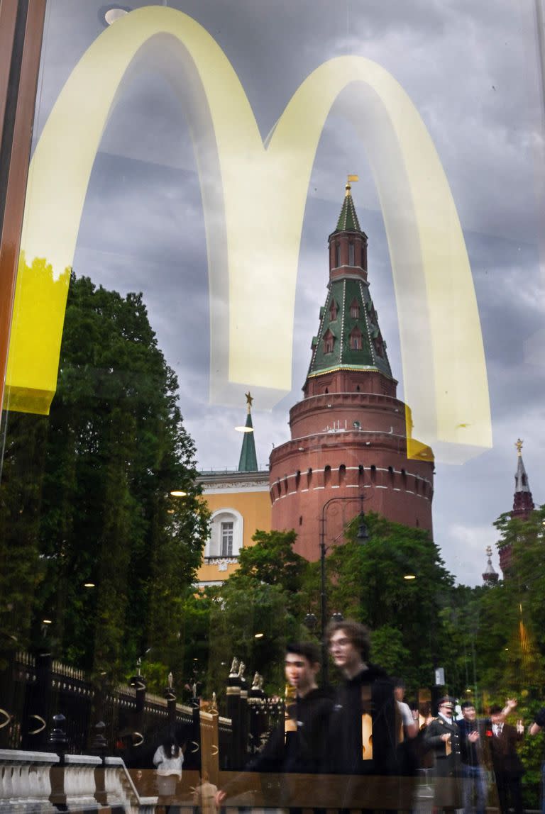 La gente pasa frente a una ventana de un restaurante McDonald's mientras las torres del Kremlin se reflejan en él en Moscú, el 26 de mayo de 2022. McDonald's llegó a un acuerdo para vender su negocio en Rusia al empresario ruso Alexander Govor, licenciatario de la cadena. (Photo by Alexander NEMENOV / AFP)