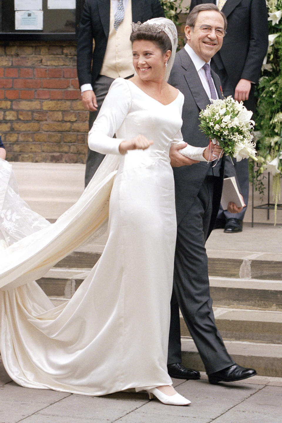 <p> In July 1999, Princess Alexia of Greece and Denmark married Carlos Javier Morales Quintana at St Sophia Catherdal in London. For the occasion, the exiled princess chose a gown by Inge Sprawson, an Austrian designer favoured by her mother, Queen Anne Marie. The elegant white satin column gown was remarkably simple from the front, with long sleeves and a fitted bodice highlighting the Princess’s svelte shape. Flourishes came from the accessories, with the Princess wearing Prince Margaret of Connaught’s lace veil, the Khedive of Egypt tiara and diamond earrings to complement the sleek look. </p>