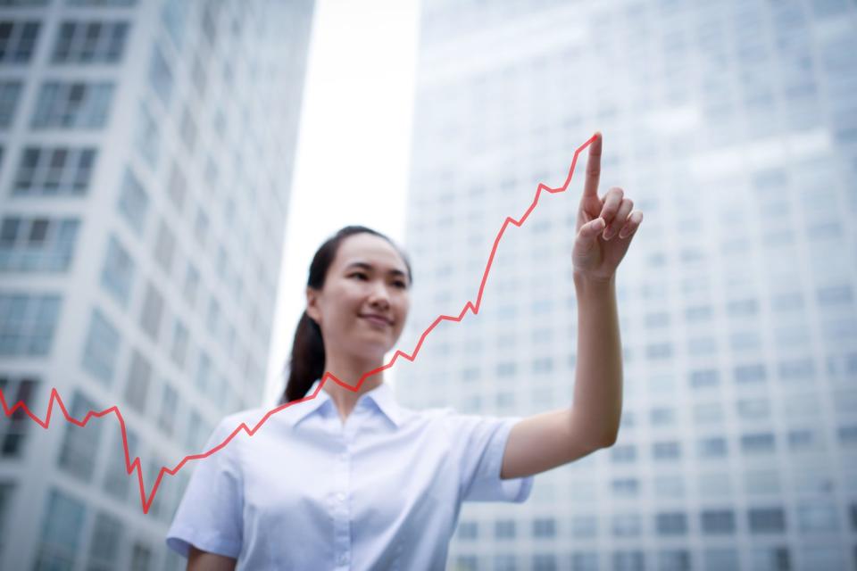 An investor standing outside in a city points to a stock performance chart in the air.