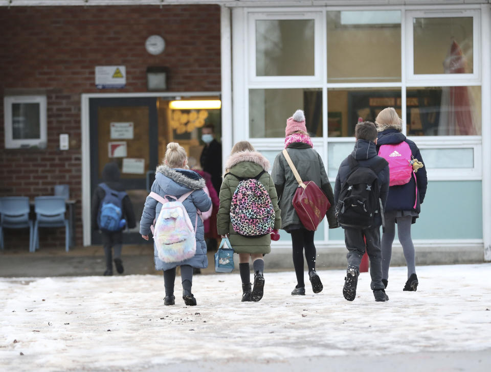 Pupils arrive at Manor Park School and Nursery in Knutsford, England, as schools across England return after the Christmas break, Monday, Jan. 4, 2021. Britain's Prime Minister Boris Johnson on Sunday insisted he has “no doubt” that schools are safe and urged parents to send their children back into the classroom Monday in areas of England where schools plan to reopen. (Martin Rickett/PA via AP)