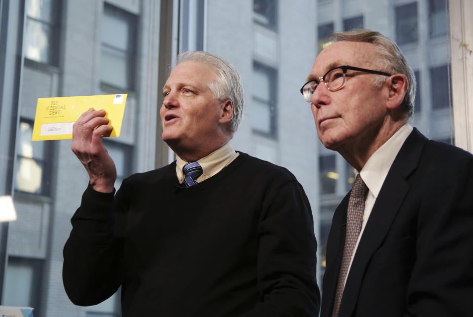 In this Dec. 19, 2018 photo, Craig Antico, left, and Jerry Ashton, co-founders of RIP Medical Debt, talks to reporters in New York. The co-founders of RIP Medical Debt buy millions of dollars in past-due medical debt for pennies on the dollar. But instead of hounding people to pay, they send letters saying the debt is erased, no strings attached. (AP Photo/Seth Wenig)