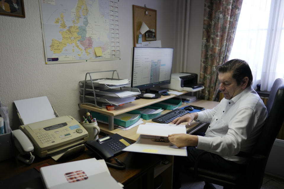 Bart Dochy looks through accounting books and logs entries on his computer at his family farm in Ledegem, Belgium, Tuesday, Feb. 13, 2024. Fickle regulations are a key complaint heard from European farmers protesting over the past weeks, setting up a key theme for the upcoming June 6-9 parliamentary elections in the 27-nation European Union. (AP Photo/Virginia Mayo)