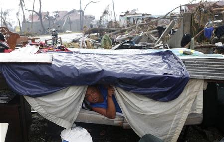 A typhoon victim looks out from a makeshift shelter along a road in Palo, Leyte province in central Philippines, which was battered by Typhoon Haiyan November 12, 2013. REUTERS/Erik De Castro