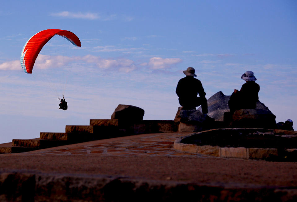 People watch as a paraglider flies past them in Sydney