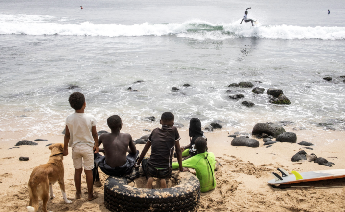 Children look on at a surfer in Dakar, Senegal - Sunday 6 March 2022