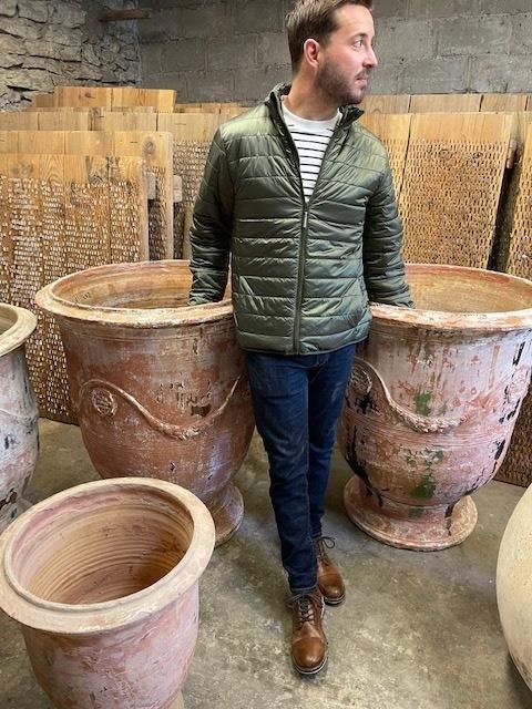 This image released by Thomas Guy Interiors shows Louisiana-based designer Lance Thomas posing with 19th Century Anduze planters that can be found at Versailles, and was popular during the reign of Louis XIV. Thomas ships antique French pots like these as well as pre-20th century olive pots, back to use on projects here at home. (Thomas Guy Interiors via AP)