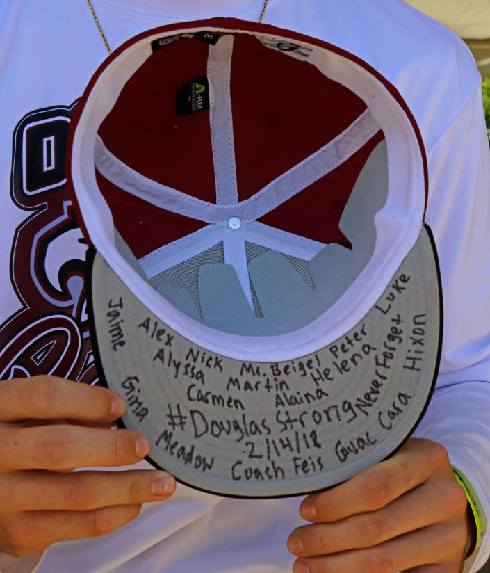 <p>Marjory Stoneman Douglas baseball player Connor Brian holds a hat with the names of the victims of the shootings at the school, before the team’s spring training baseball game against St. Louis Cardinals on Friday, Feb. 23, 2018, in Jupiter, Fla. (Photo: David Santiago/Miami Herald via AP) </p>