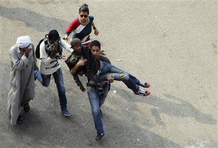 An injured protester is carried by fellow protesters after security forces fired teargas at them in Cairo's Tahrir Square November 19, 2013. REUTERS/Mohamed Abd El Ghany