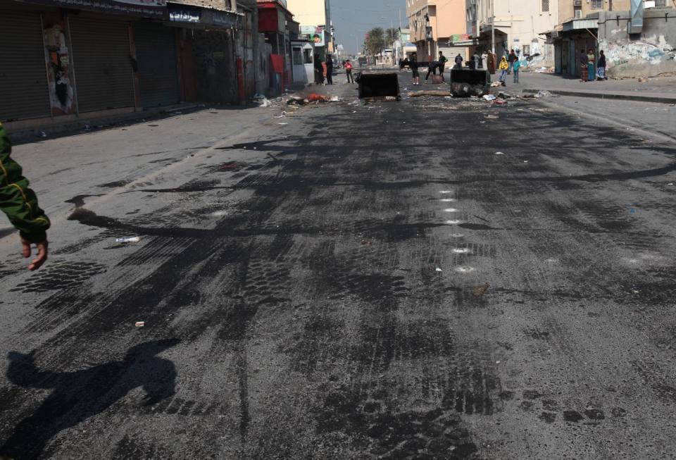 Bahraini anti-government protesters wait for riot police between clashes in the debris-filled main street of Malkiya, Bahrain, Thursday, Feb. 13, 2014. Rubbish and the oil smeared on the road are meant to deter police jeeps from entering the village, where shops were shuttered in observance of a general strike called by anti-government groups in the run-up to Friday's third anniversary of the pro-democracy uprising in the Gulf island kingdom. (AP Photo/Hasan Jamali)