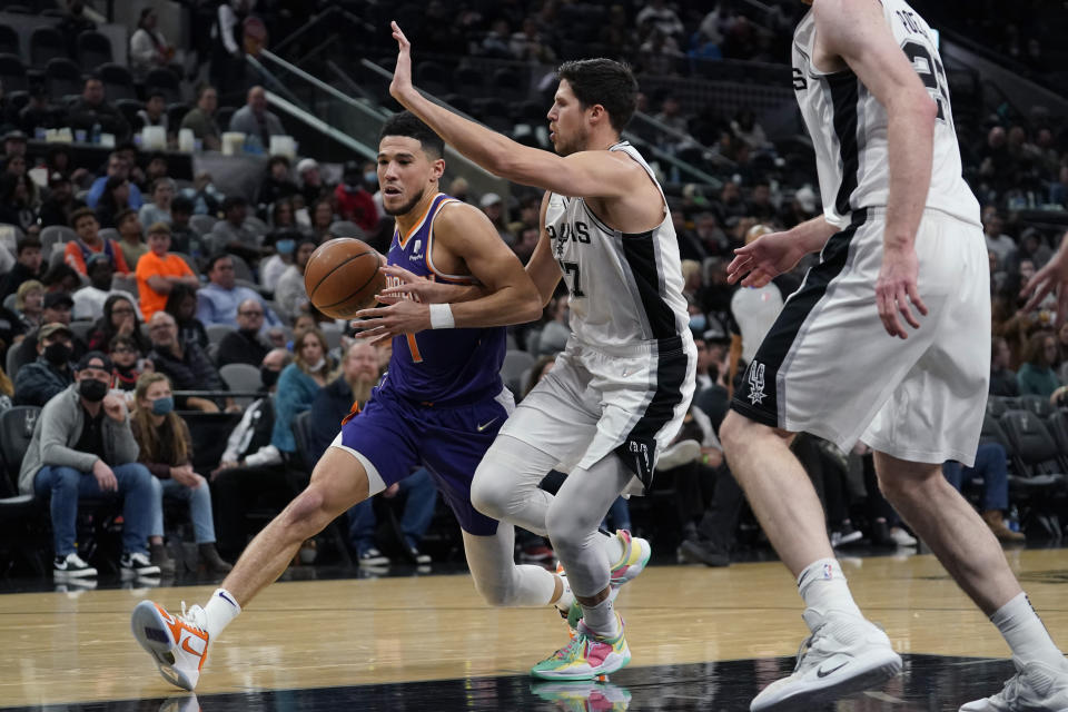 Phoenix Suns guard Devin Booker (1) drives around San Antonio Spurs forward Doug McDermott (17) during the second half of an NBA basketball game, Monday, Jan. 17, 2022, in San Antonio. (AP Photo/Eric Gay)