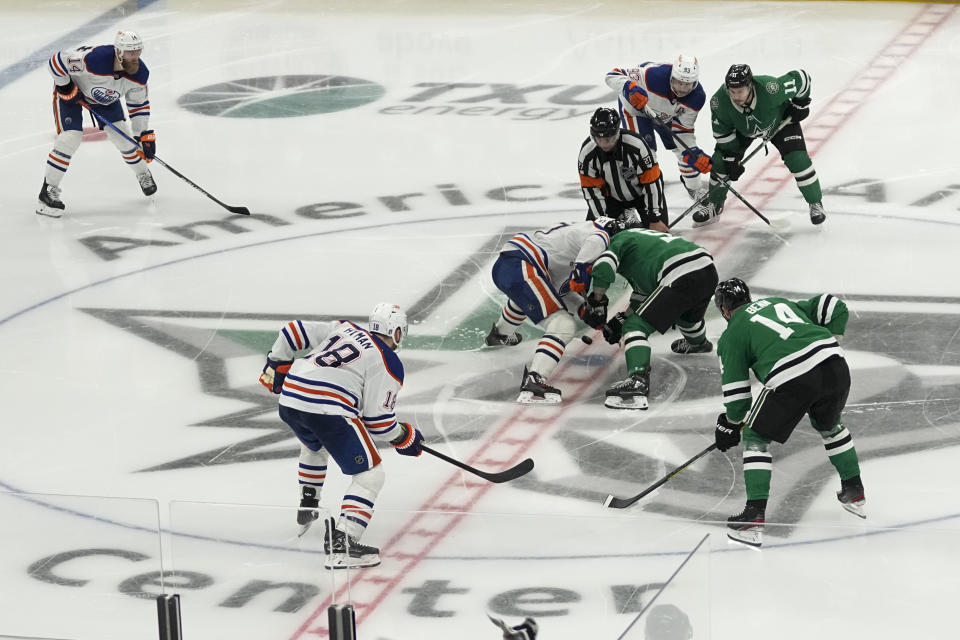 Edmonton Oilers center Connor McDavid, center left, and Dallas Stars center Wyatt Johnston (53) participate in the puck drop at the beginning of the second overtime in Game 1 of the NHL hockey Western Conference Stanley Cup playoff finals, Thursday, May 23, 2024, in Dallas. (AP Photo/Tony Gutierrez)