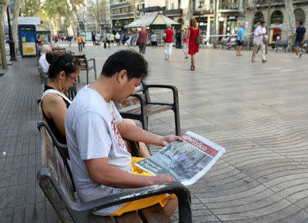 A man sits on a bench as he reads a newspaper at Las Ramblas street where a van crashed into pedestrians in Barcelona, Spain August 18, 2017. REUTERS/Sergio Perez