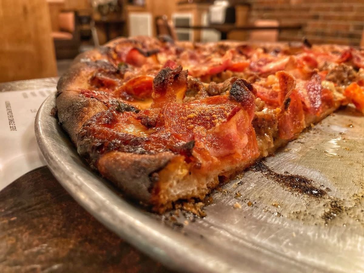 Closeup of pepperoni and sausage pizza on a serving tray, Ernie’s, New Haven, Connecticut, selective focus, on table with a receipt under the tray, restaurant blurred in the background