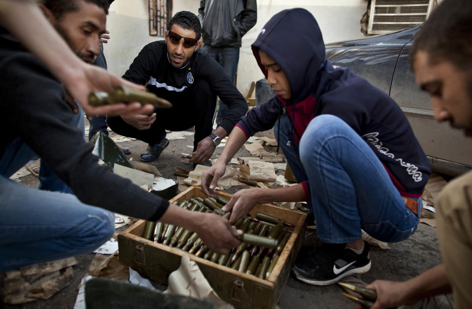 FILE - In this Monday, Feb. 28, 2011 file photo, Libyan militia members who are part of the forces against Libyan leader Moammar Gadhafi organize their munitions at a military base in Benghazi, eastern Libya. At the heart of the Libyan capital, the open-air Fish Market was once where residents went to buy everything from meat and seafood to clothes and pets. Now it’s Tripoli’s biggest arms market, with tables displaying pistols and assault rifles. Ask a vendor, and he can pull out bigger machine guns to sell for thousands of dollars. (AP Photo/Kevin Frayer, File)