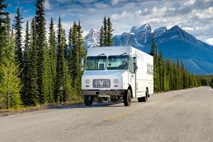 Xos stepvan driving in mountanious wooded area.