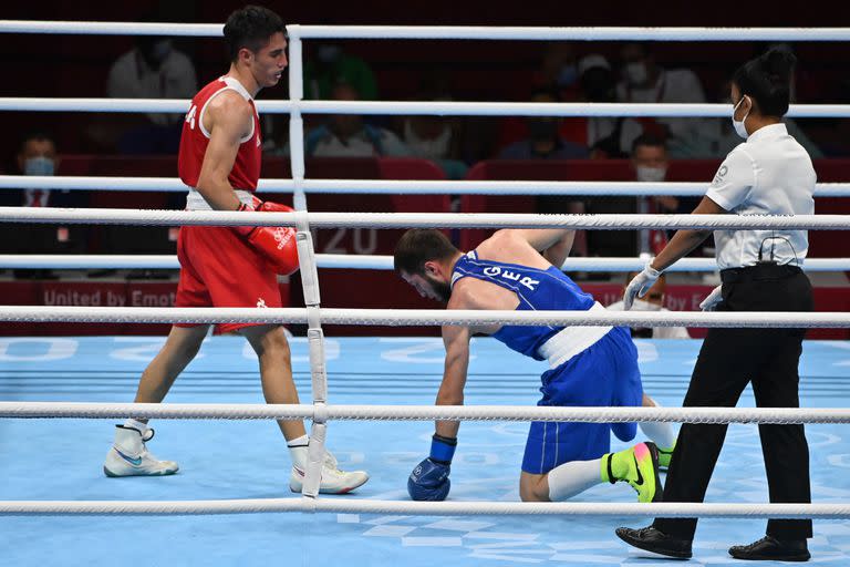 El alemán Hamsat Shadalov (azul) cae mientras pelea contra el argentino Mirco Jehiel Cuello (rojo) durante su combate de boxeo preliminar de plumas masculinas (52-57 kg) durante los Juegos Olímpicos de Tokio 2020 en el Kokugikan Arena de Tokio el 24 de julio de 2021.