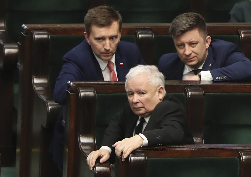 Jaroslaw Kaczynski, center, leader of the conservative ruling party Law and Justice, talks to members of his party in parliament in Warsaw, Poland, Friday April 3, 2020. Uncertainty deepened in Poland on Friday over whether the country will move forward with a presidential election scheduled for May despite the coronavirus pandemic. Kaczynski had hoped to move forward with the vote despite the epidemic by having a postal election, but the head of a faction in his coalition is opposed and wants the elections postponed by two years.(AP Photo/Czarek Sokolowski)