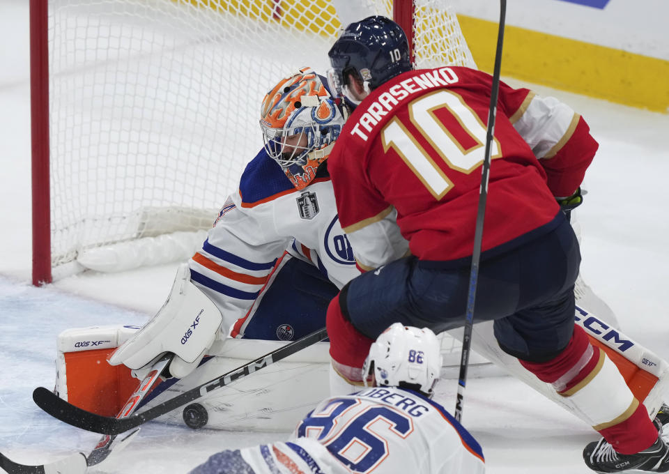 Edmonton Oilers goaltender Stuart Skinner, top left, makes a pad-save against Florida Panthers' Vladimir Tarasenko (10) during the second period of Game 1 of the NHL hockey Stanley Cup Finals in Sunrise, Fla., Saturday, June 8, 2024. (Nathan Denette/The Canadian Press via AP)