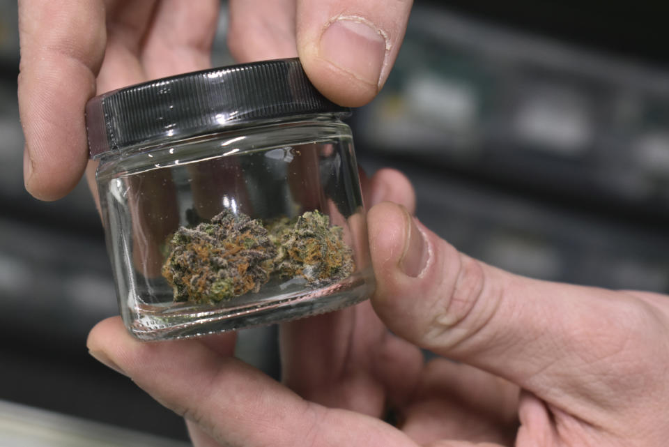 A worker holds up a jar with marijuana offered for sale at Montana Advanced Caregivers, a medical marijuana dispensary, Nov. 11, 2020, in Billings, Mont. Recreational marijuana initiatives passed in four states this year, from liberal New Jersey to conservative Montana and South Dakota. The results prove how broadly accepted marijuana has become throughout the country and across party lines. (AP Photo/Matthew Brown)