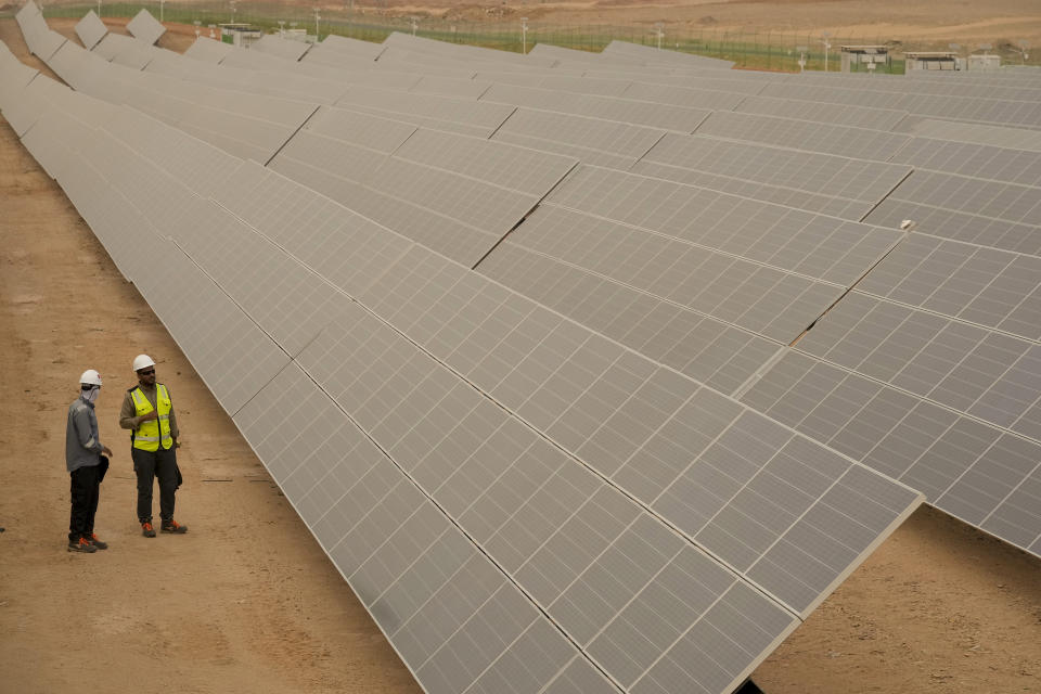Engineers talk next to photovoltaic solar panels at Benban Solar Park, one of the world's largest solar power plant in the world, in Aswan, Egypt, Oct. 19, 2022. The Arab world’s most populous country is taking steps to convert to renewable energy. But the developing country, like others, faces obstacles in making the switch. (AP Photo/Amr Nabil)