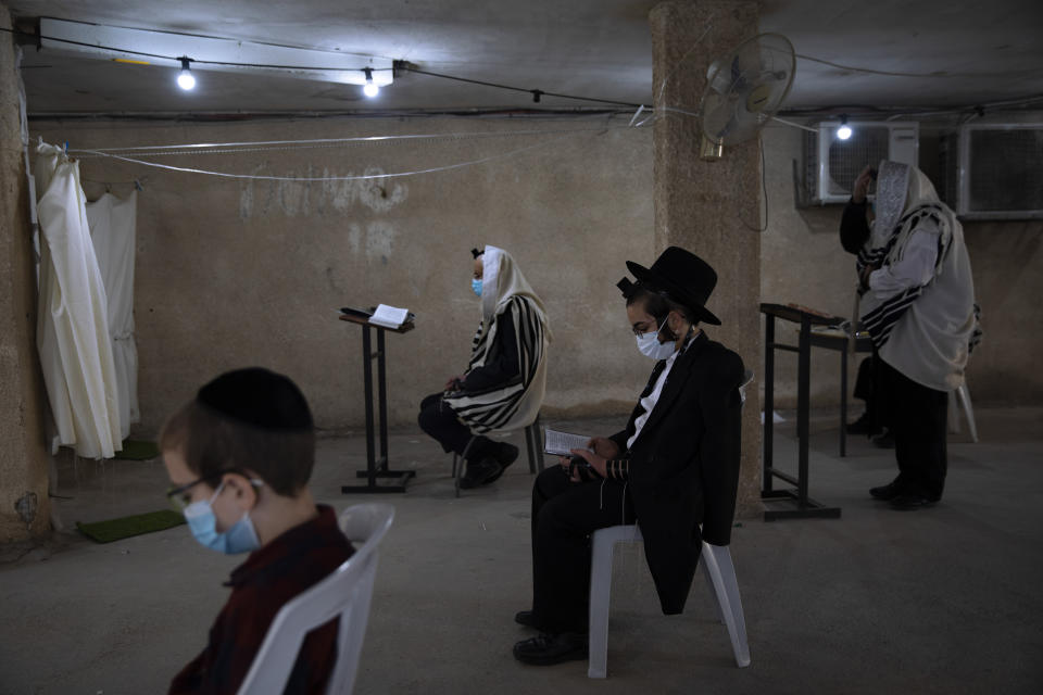 Ultra-Orthodox Jews wear face masks and keep social distancing during a morning prayer next to their houses as synagogues are closed during a nationwide lockdown to curb the spread of the coronavirus, in Bnei Brak, Israel, Friday Jan. 8, 2021. Israel has seen a surge in cases, leading authorities to tighten an already existing lockdown. Most schools and businesses will be closed starting Friday, with public gatherings restricted for a two-week period. (AP Photo/Oded Balilty)