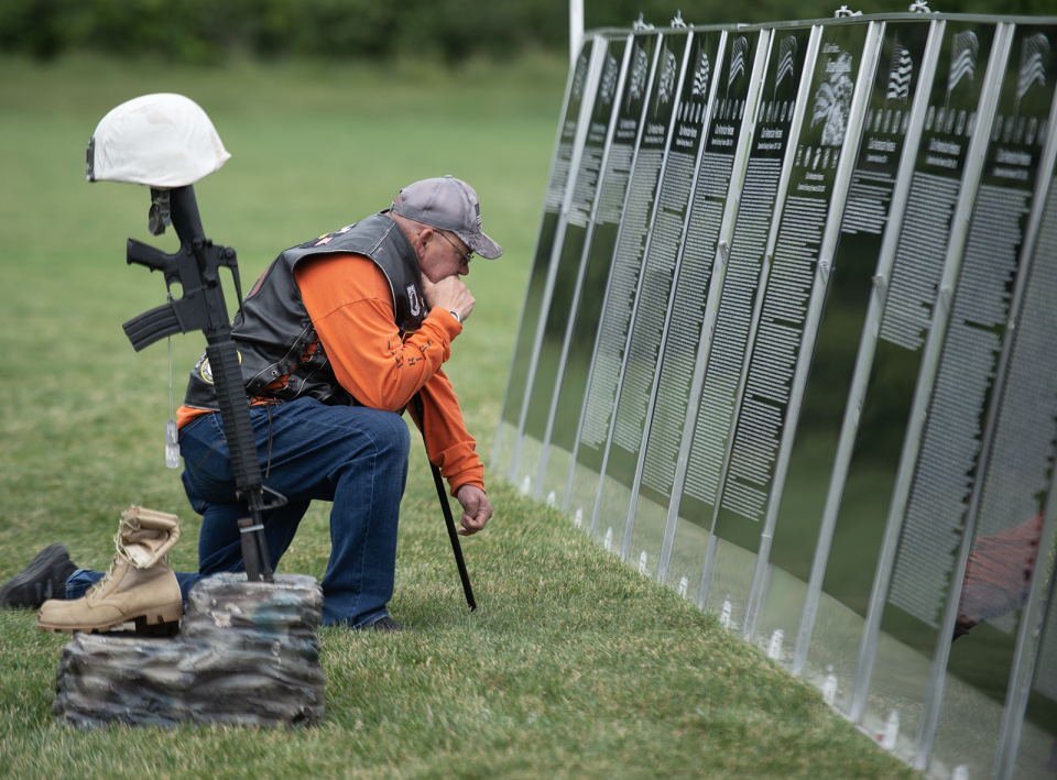 Jeff Myers reads the names on panels dedicated to more recent casualties in Iraq and Afghanistan on the Vietnam Traveling Memorial Wall, which is on display through Sunday in Aurora.