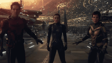 A trio of superheroes stand near a futuristic city