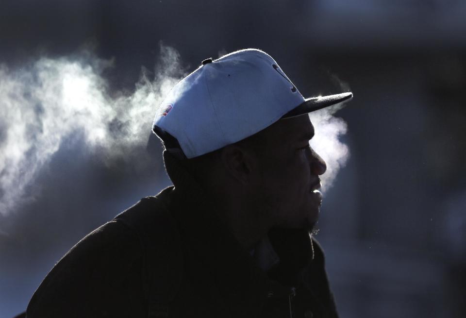 Victor Winters waits for a bus in Detroit, Tuesday, Jan. 7, 2014. Temperatures broke record lows Tuesday in Michigan and residents braced against bitter winds following a storm that shuttered schools, closed government offices and contributed to at least six deaths. Lows of 14 degrees below zero were reported according to the National Weather Service. (AP Photo/Paul Sancya)