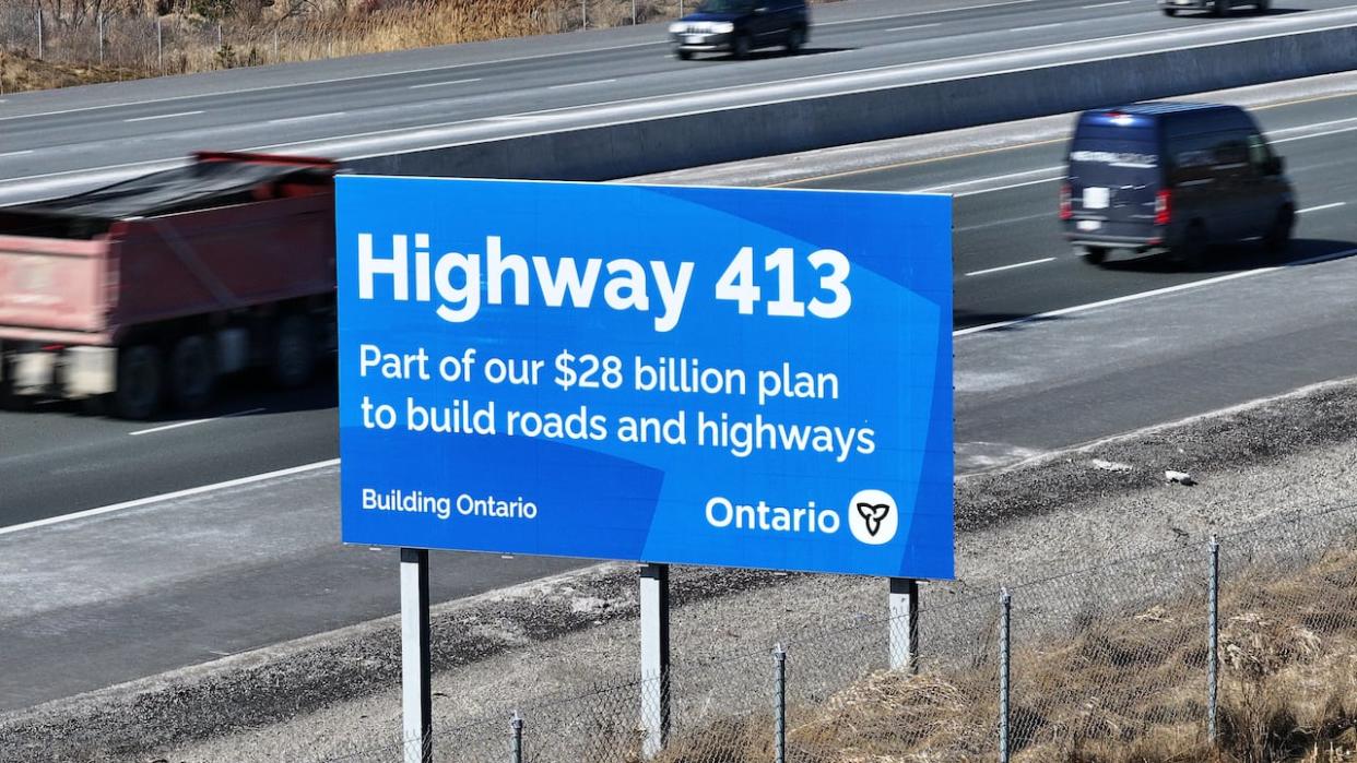 An aerial photo of Highway 400 in King City, with the Ontario government billboard announcing the future site of Highway 413. A joint filing in federal court shows the two levels of government have agreed to drop an assessment of the project. (Patrick Morrell/CBC News - image credit)