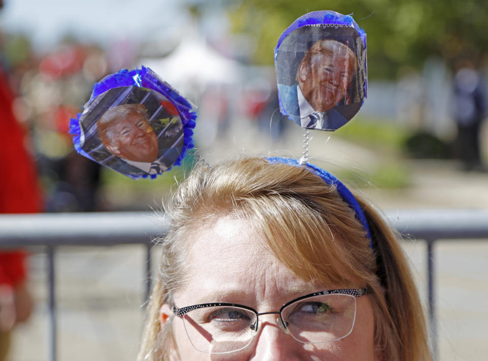 President Donald Trump "bobbers" sits on head of Amanda Varner of Florence, Miss., while she waits outside the BancorpSouth Arena in Tupelo, Miss., Friday, Nov. 1, 2019, before a Keep America Great Rally. (AP Photo/Rogelio V. Solis)