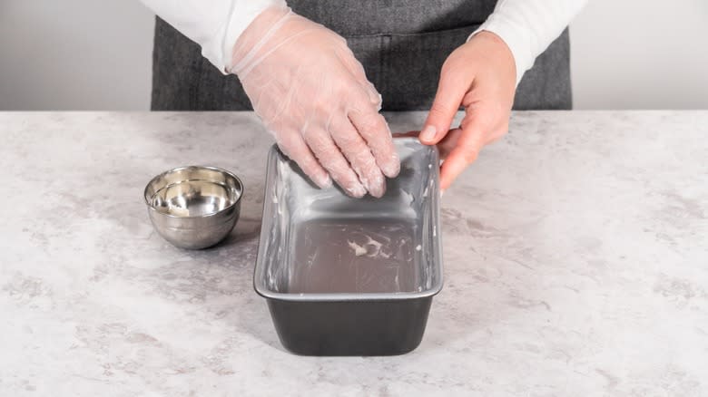 Person greasing loaf pan