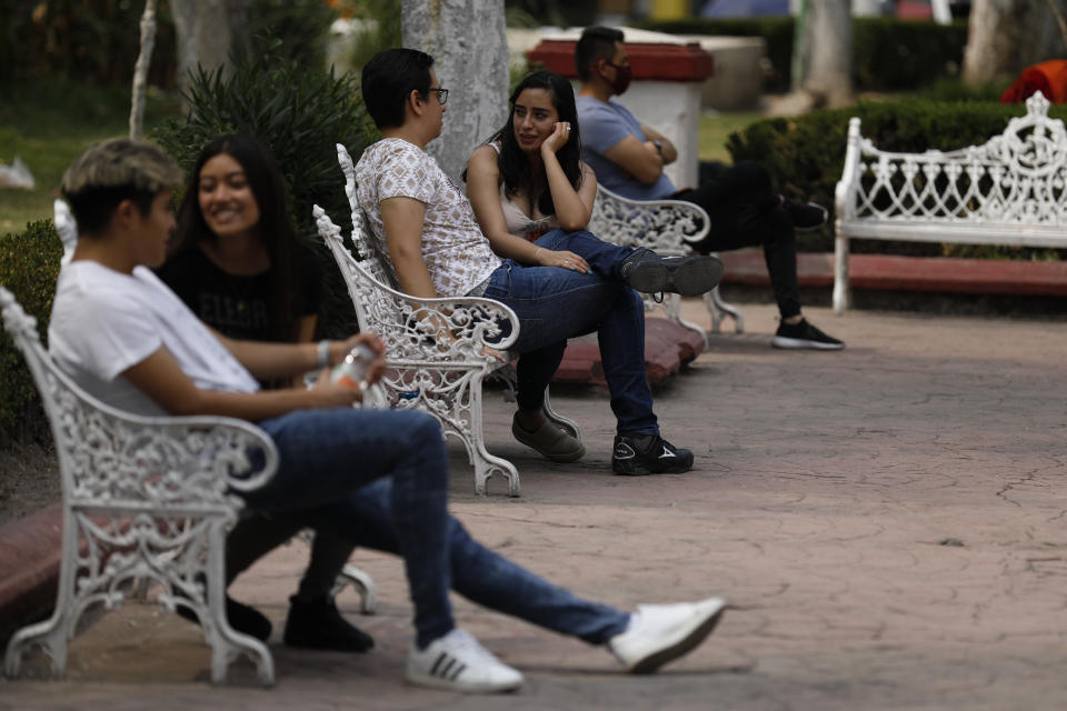 People pass the time in a public plaza in Ecatepec, a Mexico City suburb, Wednesday, May 20, 2020. Mexico City, one of the world's largest cities and the epicenter of the country's coronavirus epidemic, will begin a gradual reopening June 1, its mayor said Wednesday, even as daily new infections continued to set records.(AP Photo/Rebecca Blackwell)