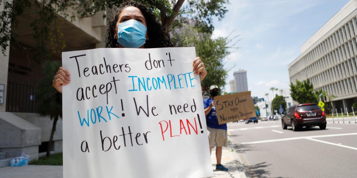 First grade teacher Yolanda Vasquez (R) stands in protest along with other teachers and counselors in front of the Hillsborough County Schools District Office on July 16, 2020 in Tampa, Florida. Teachers and administrators from Hillsborough County Schools rallied against the reopening of schools due to health and safety concerns amid the COVID-19 pandemic.