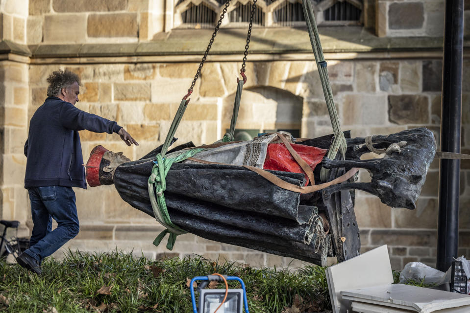 The sculpture of Essen Cardinal Franz Hengsbach hangs on a crane in front of Essen Cathedral after being dismantled and loaded in Essen, Germany, Monday Sept. 25, 2023. A statue of late German Cardinal Franz Hengsbach was removed from outside a cathedral in western Germany after allegations of sexual abuse against him surfaced. (Christoph Reichwein/dpa via AP)