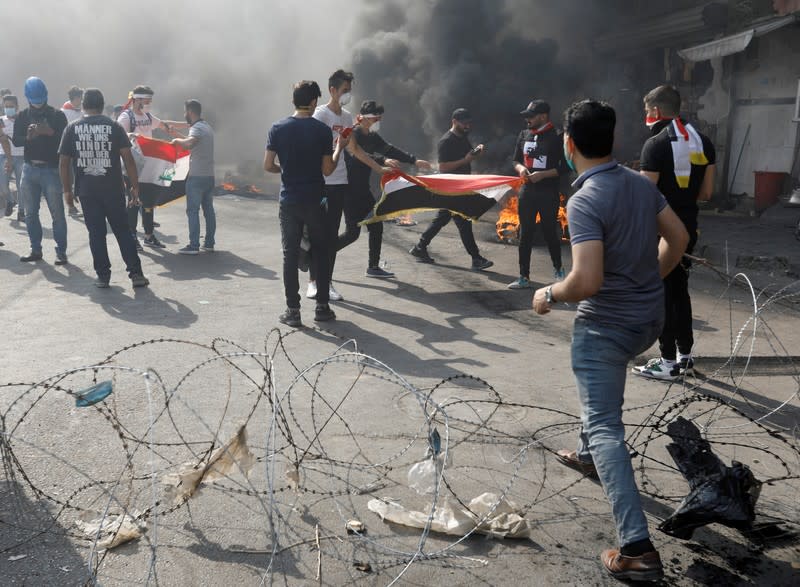 Iraqi demonstrators burn tires as they block the road during ongoing anti-government protests, in Baghdad