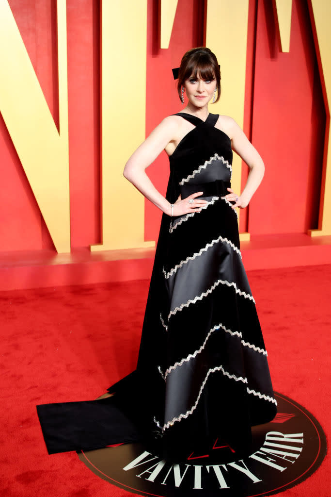 Woman in elegant black and white gown posing on Vanity Fair event carpet