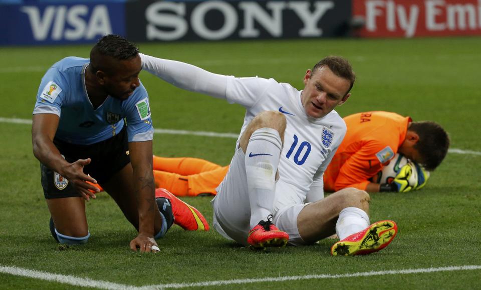 England's Rooney falls next to Uruguay's Pereira after missing a chance to score during their 2014 World Cup Group D soccer match in Sao Paulo