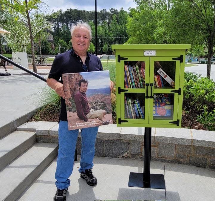 Steve Cloer holds a photo of his son, Benjamin Cloer, next to the Little Library dedicated in his son's name in Peachtree Corners in Gwinnett County.