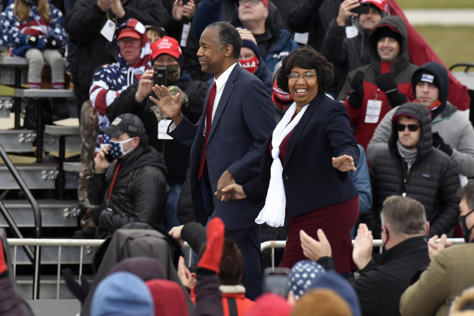 Housing and Urban Development Secretary Ben Carson, left, and his wife, Candy Carson, walk on stage at a campaign rally for President Donald Trump at Oakland County International Airport, Friday, Oct. 30, 2020, in Waterford Township, Mich. (AP Photo/Jose Juarez)