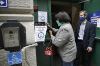 A voter, left, places a ballot in a secure box as Providence City Clerk Shawn Selleck, right, looks on, Tuesday, June 2, 2020, in Providence, R.I. Because so many voters asked for mail ballots, state electoral officials say mail ballots can be dropped off Tuesday at secure boxes outside city and town halls across Rhode Island. (AP Photo/Steven Senne)