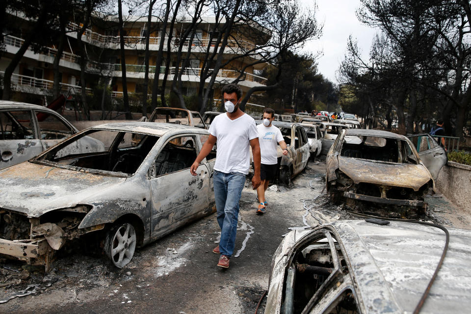 <p>Locals wearing masks walk among burnt cars following a wildfire at the village of Mati, near Athens, Greece, July 24, 2018. (Photo: Costas Baltas/Reuters) </p>