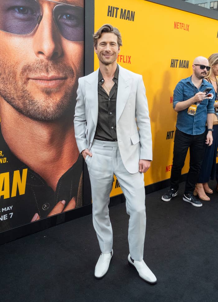 Glen Powell in a white suit and black shirt at the 'Hit Man' Netflix event