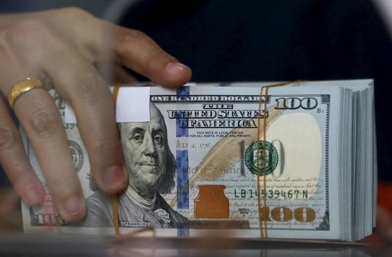 An employee of a money changer holds a stack of U.S. Dollar notes before giving it to a customer in Jakarta, October 8, 2015. REUTERS/Beawiharta