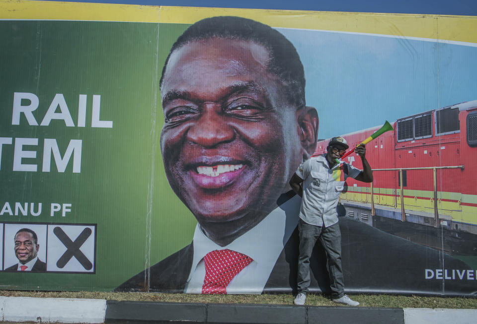 A man blows a horn at a ruling ZANU PF election rally in Harare, Zimbabwe on Saturday July 28, 2018. Zimbabwean President Emmerson Mnangagwa, shown on poster, and main challenger Nelson Chamisa are set to hold final campaign rallies ahead of Monday's election in a country seeking to move past decades of economic and political paralysis. (AP Photo)